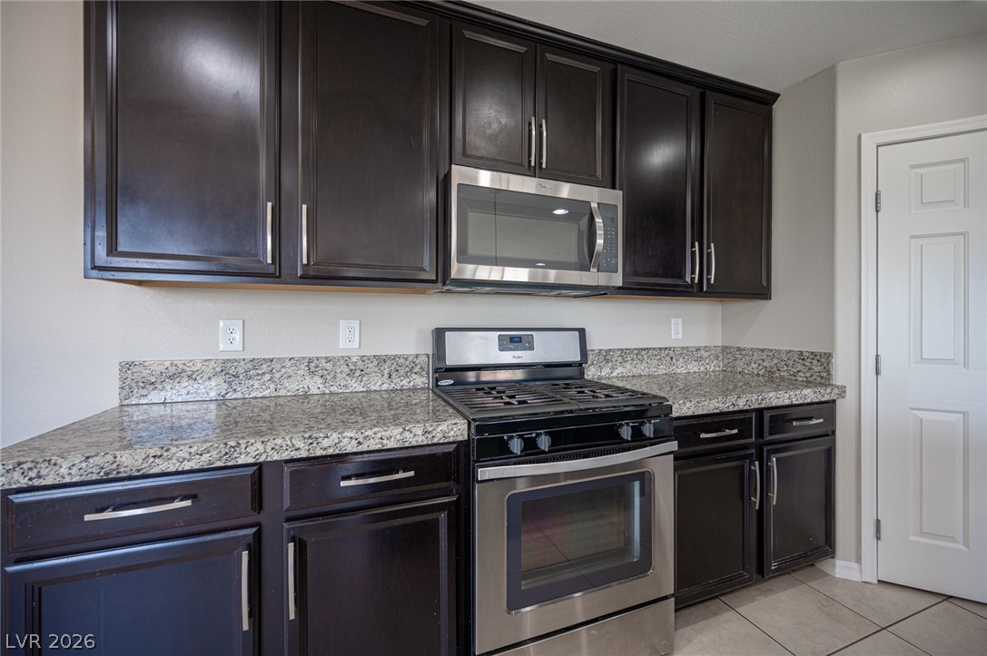 9916 Sable Point Street Las Vegas, NV 89178 - Photo 34 of 73 A well-appointed kitchen showcasing dark cabinetry, granite countertops, and stainless steel appliances.