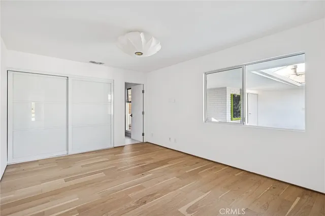 a view of an empty room with wooden floor and a mirror