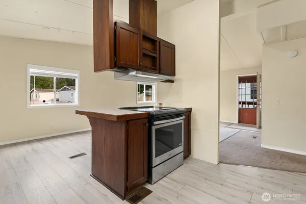 a kitchen with stainless steel appliances a stove microwave and wooden floor