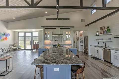 a kitchen with stainless steel appliances granite countertop a kitchen island a stove and a wooden floors