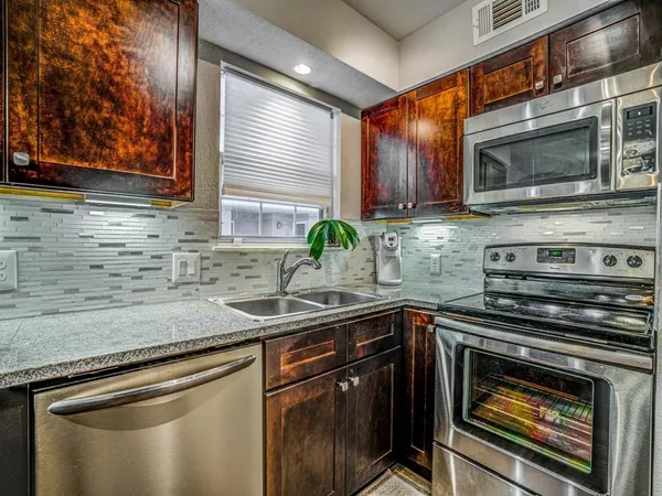 a kitchen with stainless steel appliances granite countertop a sink stove and microwave