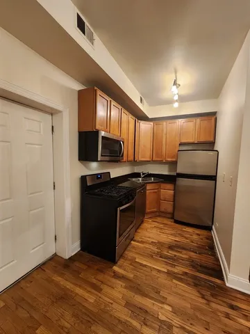 a kitchen with granite countertop a refrigerator and a stove top oven