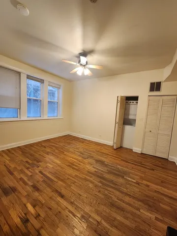 a view of an empty room with window and wooden floor