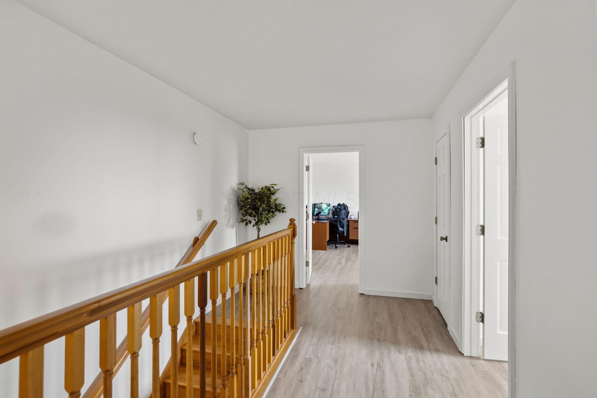 10446 Rich Hollow Road Southwest Lancaster, OH 43130 - Photo 62 of 83 Hallway featuring light wood-finish flooring, white walls, and a natural wood staircase with balusters