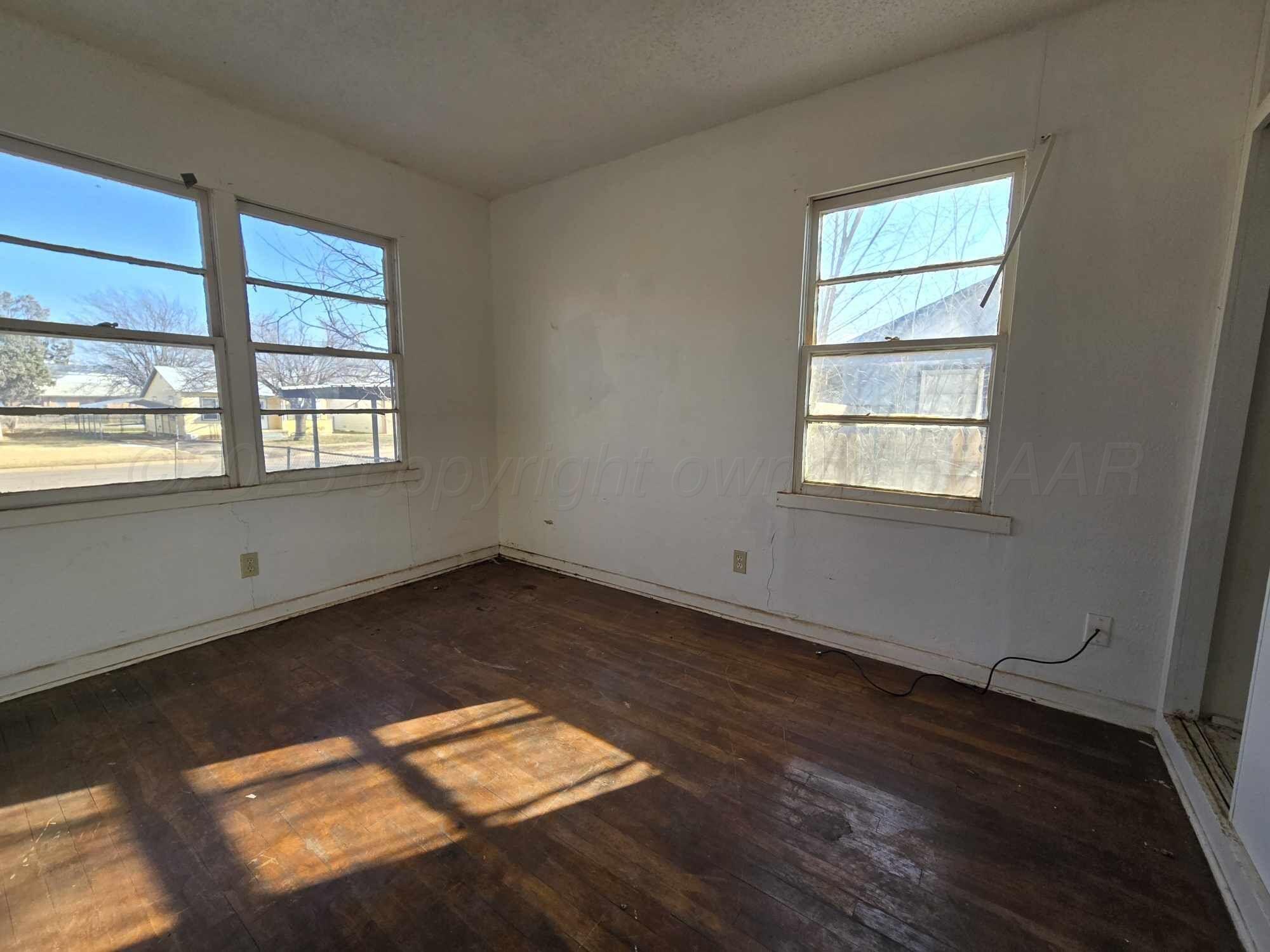 508 South Collins Avenue Tulia, TX 79088 - Photo 5 of 11 an empty room with wooden floor and windows