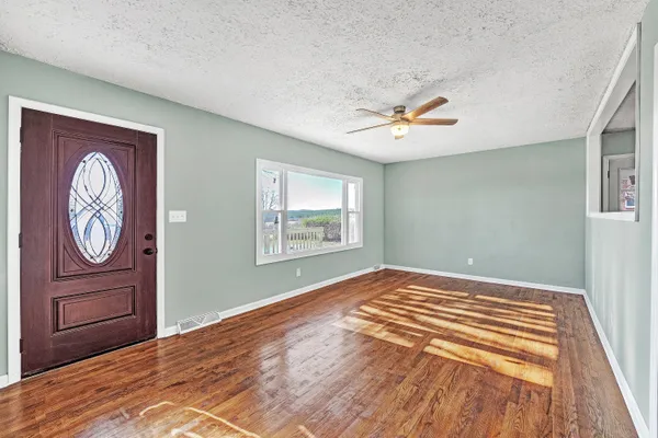 a view of an empty room with window and wooden floor