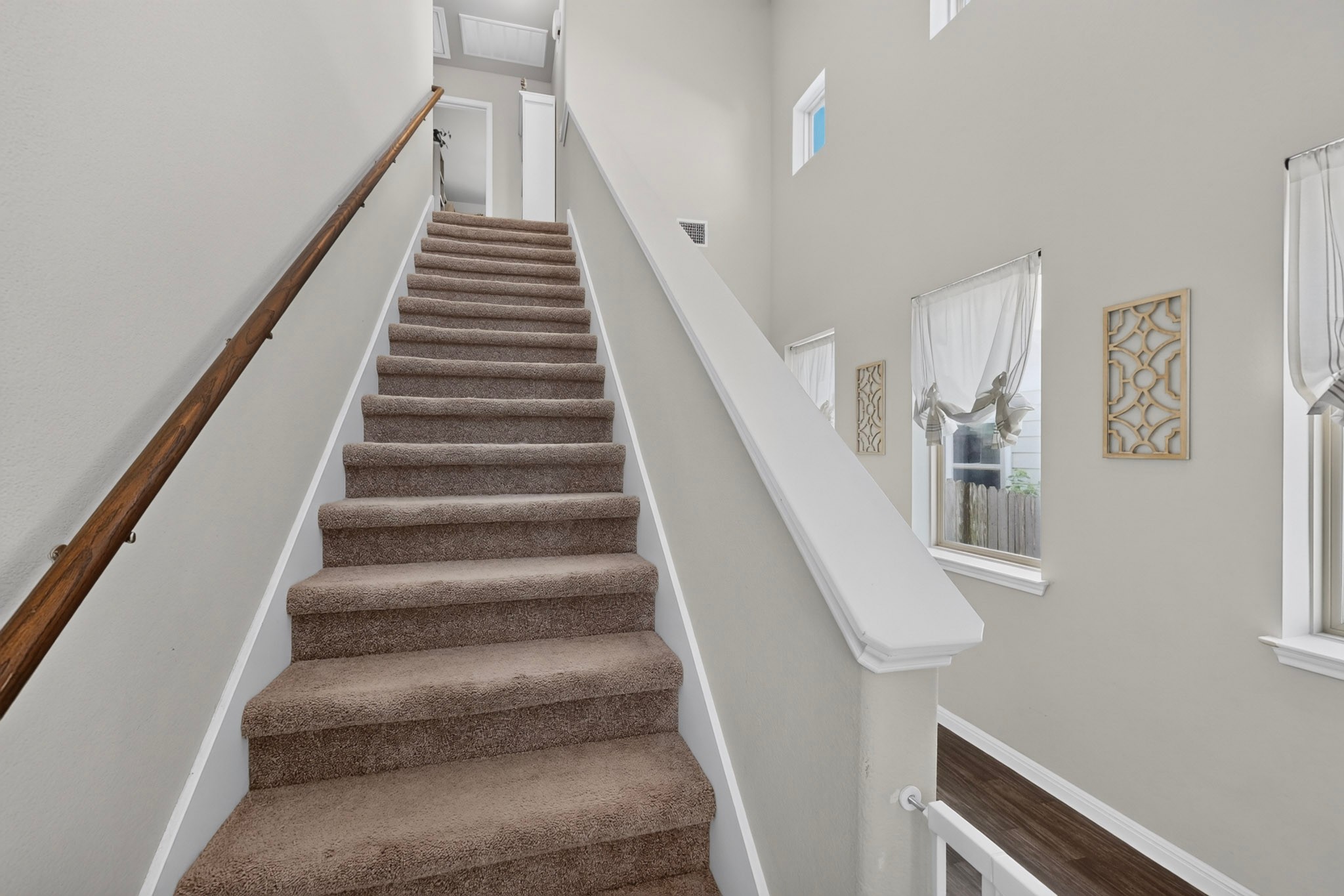 132 Wapiti Road Buda, TX 78610 - Photo 21 of 31 Ascend to comfort on carpeted stairs, illuminated by a high ceiling and ample natural light.