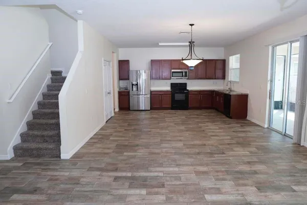 a kitchen with stainless steel appliances granite countertop a stove top oven a refrigerator a sink and dishwasher with wooden floor