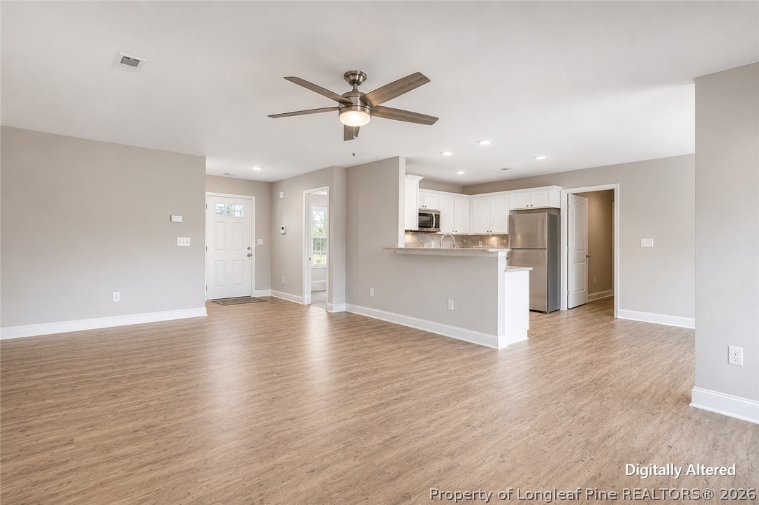 756 Jordan Road Autryville, NC 28318 - Photo 22 of 34 a view of a kitchen with a refrigerator a ceiling fan and wooden floor