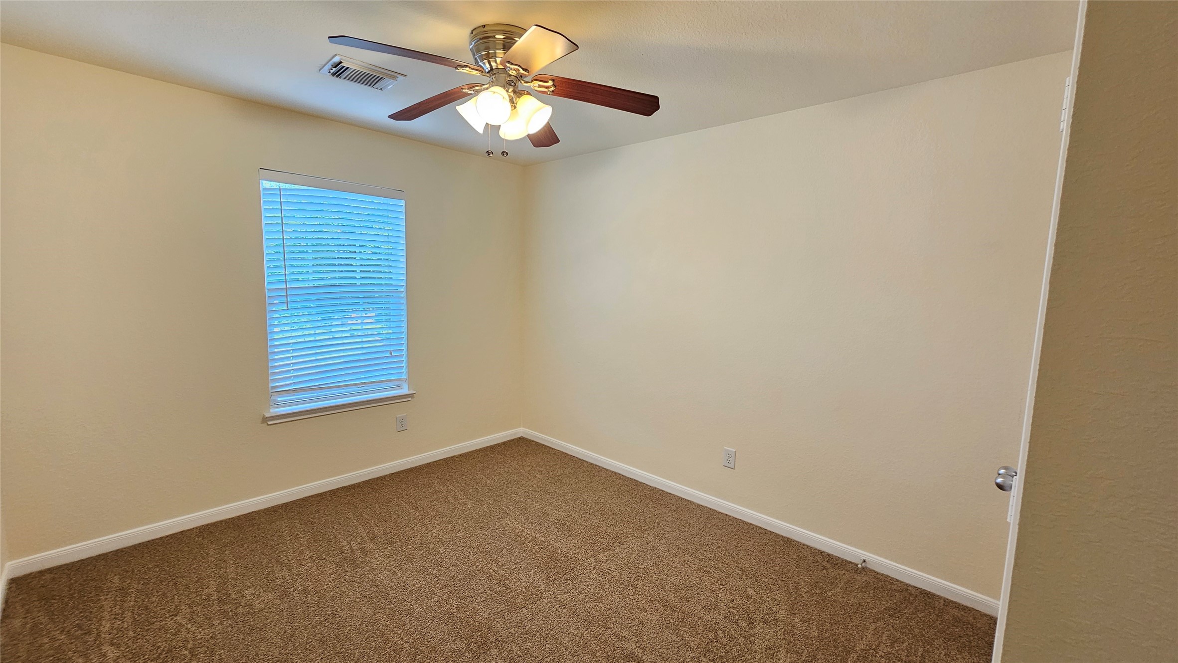 7918 Barnes Ridge Lane Houston, TX 77072 - Photo 13 of 34 This is a cozy, carpeted bedroom with neutral walls, a ceiling fan with lights, and a window with blinds, providing a bright and inviting atmosphere.