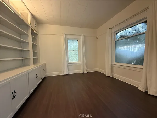 a view of an empty room with closet and wooden floor