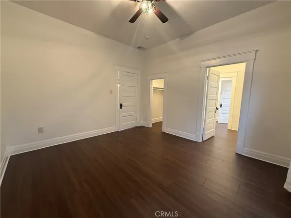 an empty room with wooden floor chandelier fan and windows
