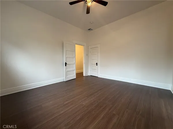 an empty room with wooden floor ceiling fan and window