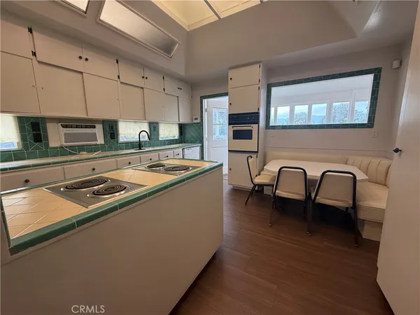 a kitchen that has a stove a sink and a dining table with granite countertop wooden floor