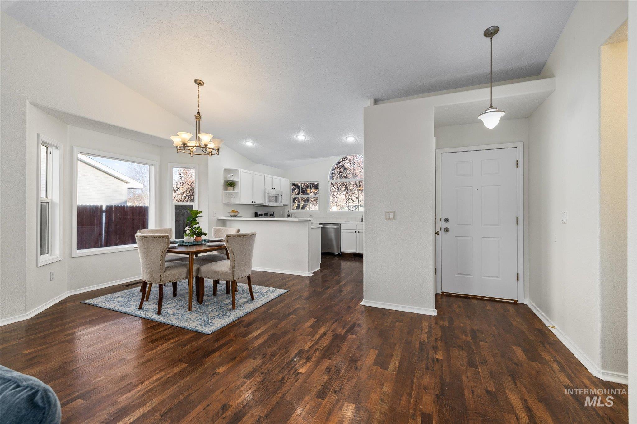 1399 West Gander Drive Meridian, ID 83642 - Photo 11 of 40 Dining space with vaulted ceiling, a chandelier, healthy amount of natural light, and dark wood-style flooring