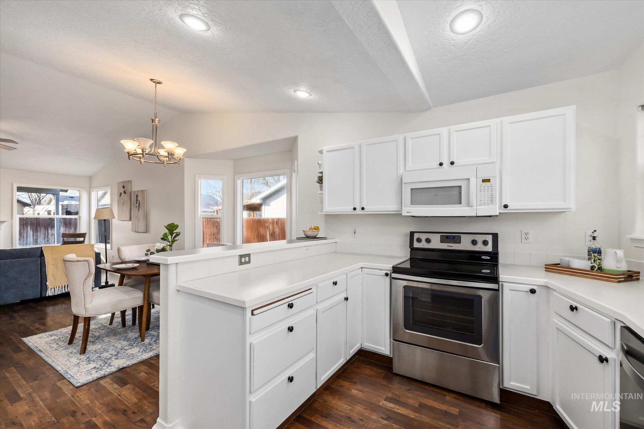 1399 West Gander Drive Meridian, ID 83642 - Photo 13 of 40 Kitchen featuring a peninsula, appliances with stainless steel finishes, white cabinetry, pendant lighting, and vaulted ceiling
