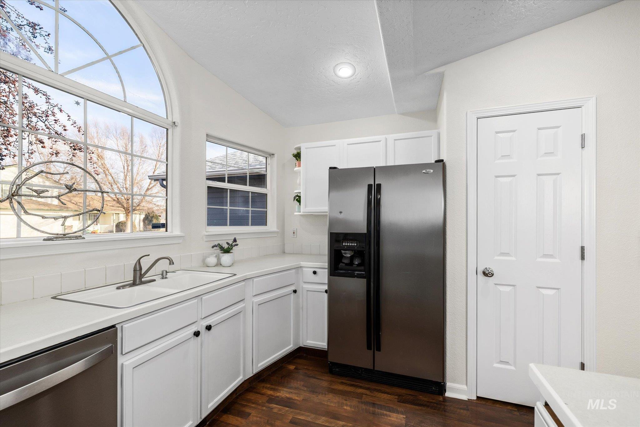 1399 West Gander Drive Meridian, ID 83642 - Photo 16 of 40 Kitchen featuring appliances with stainless steel finishes, light countertops, white cabinets, a textured ceiling, and dark wood-style floors