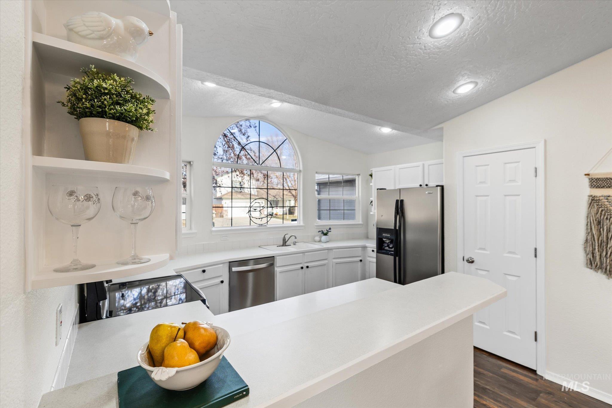 1399 West Gander Drive Meridian, ID 83642 - Photo 17 of 40 Kitchen featuring light countertops, open shelves, lofted ceiling, stainless steel appliances, and a textured ceiling