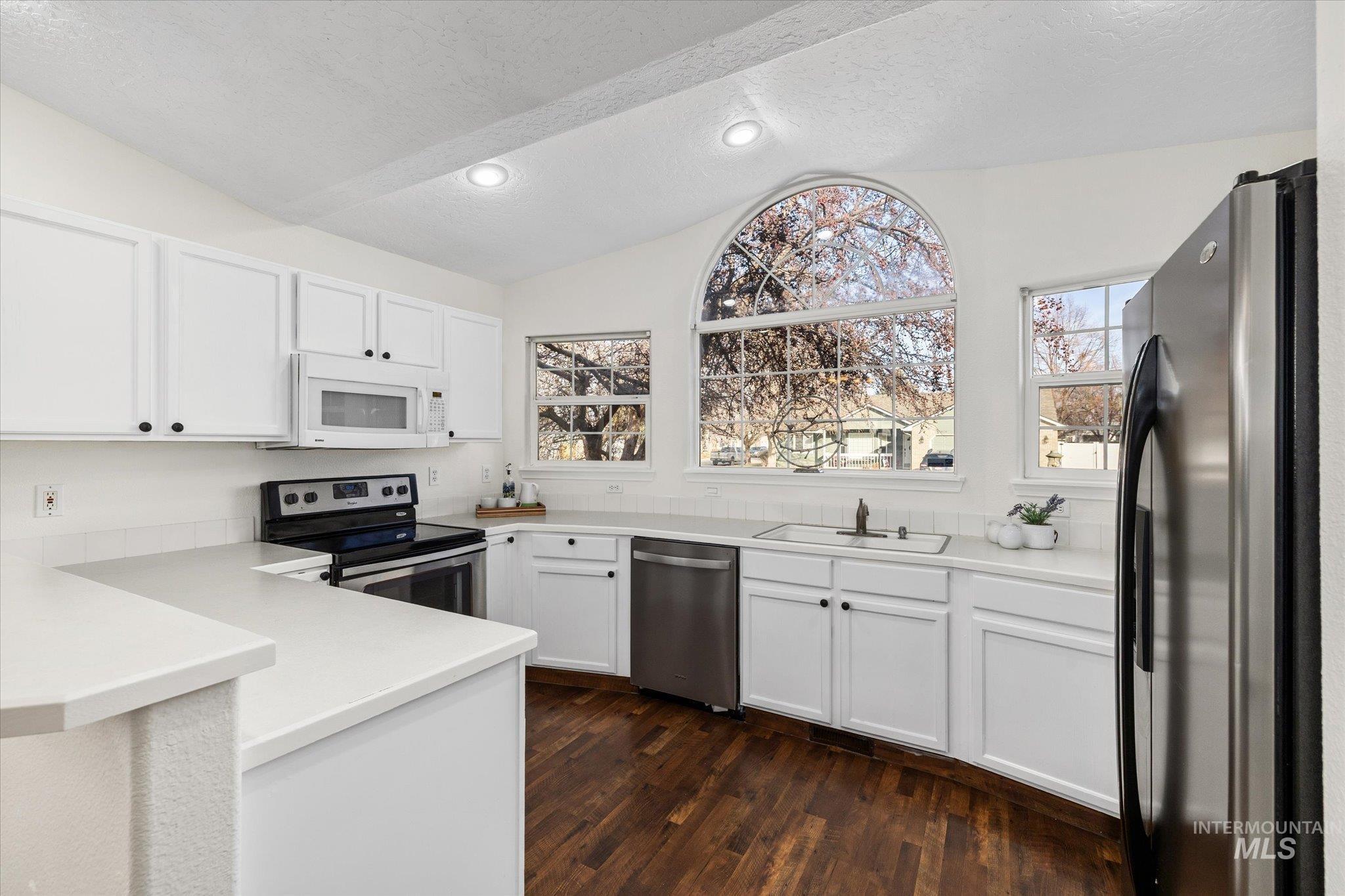 1399 West Gander Drive Meridian, ID 83642 - Photo 18 of 40 Kitchen with stainless steel appliances, lofted ceiling, white cabinetry, dark wood finished floors, and a textured ceiling