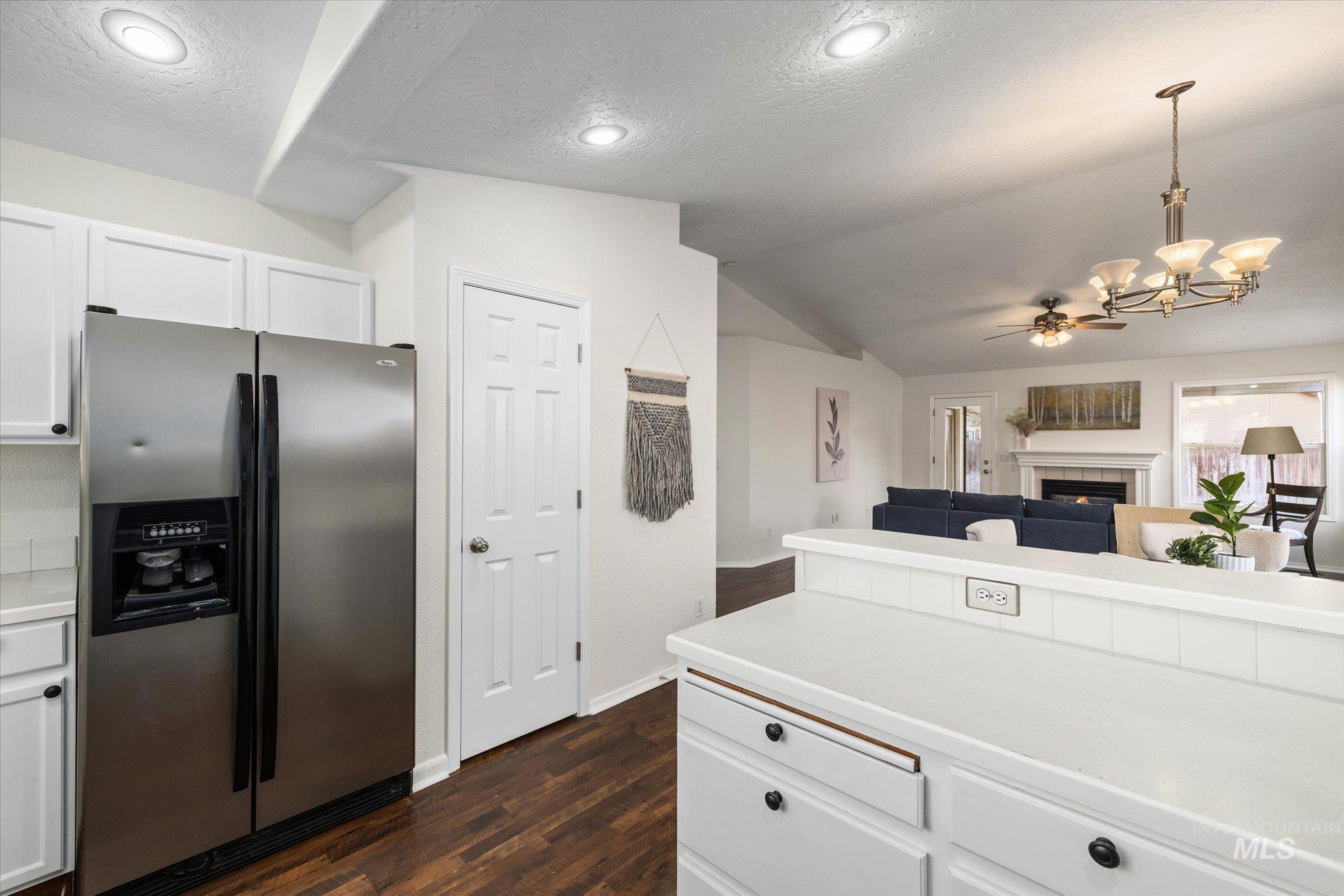 1399 West Gander Drive Meridian, ID 83642 - Photo 19 of 40 Kitchen with stainless steel fridge with ice dispenser, light countertops, a fireplace, white cabinetry, and lofted ceiling