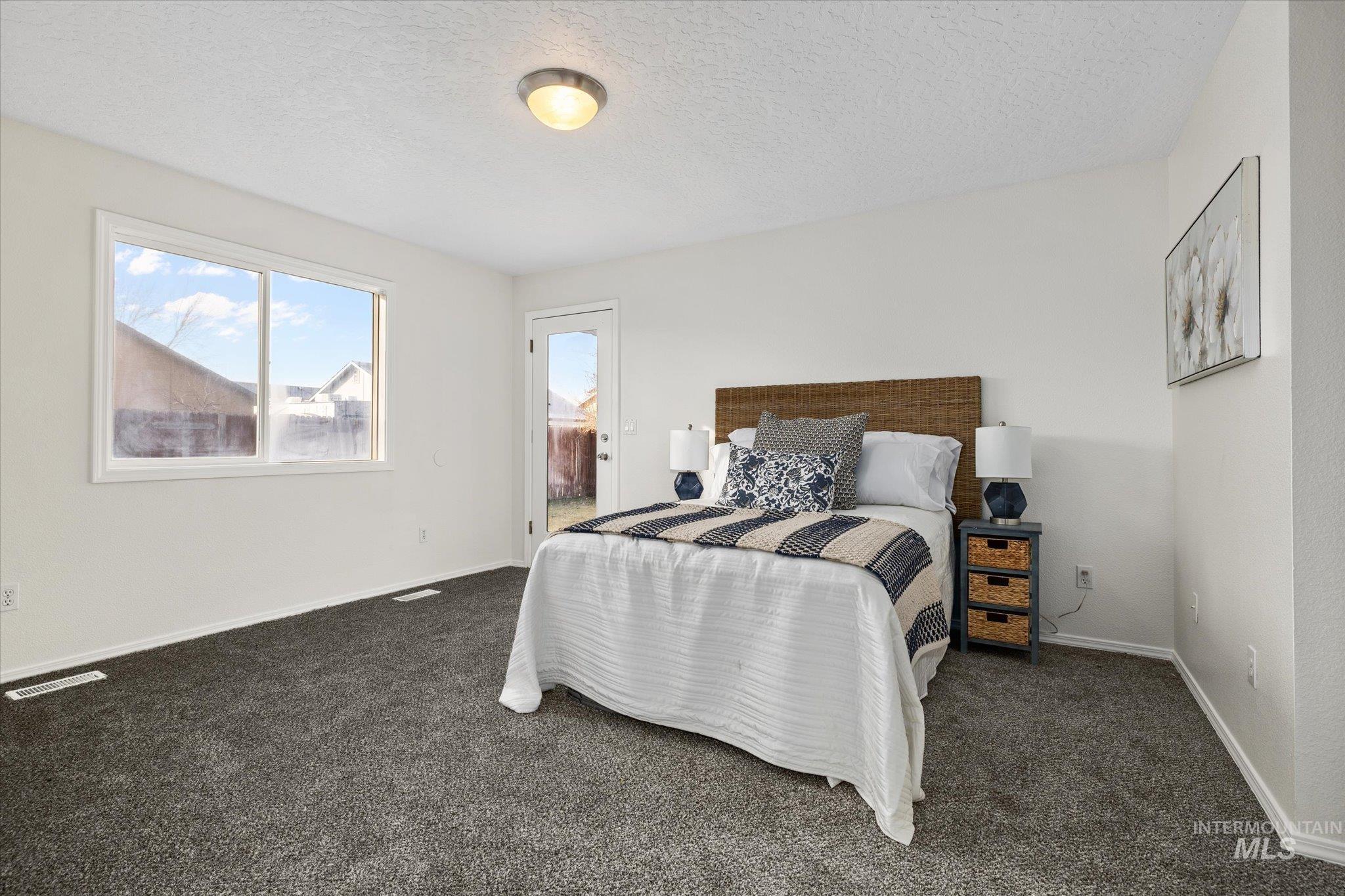1399 West Gander Drive Meridian, ID 83642 - Photo 20 of 40 Bedroom featuring access to outside, a textured ceiling, and dark colored carpet