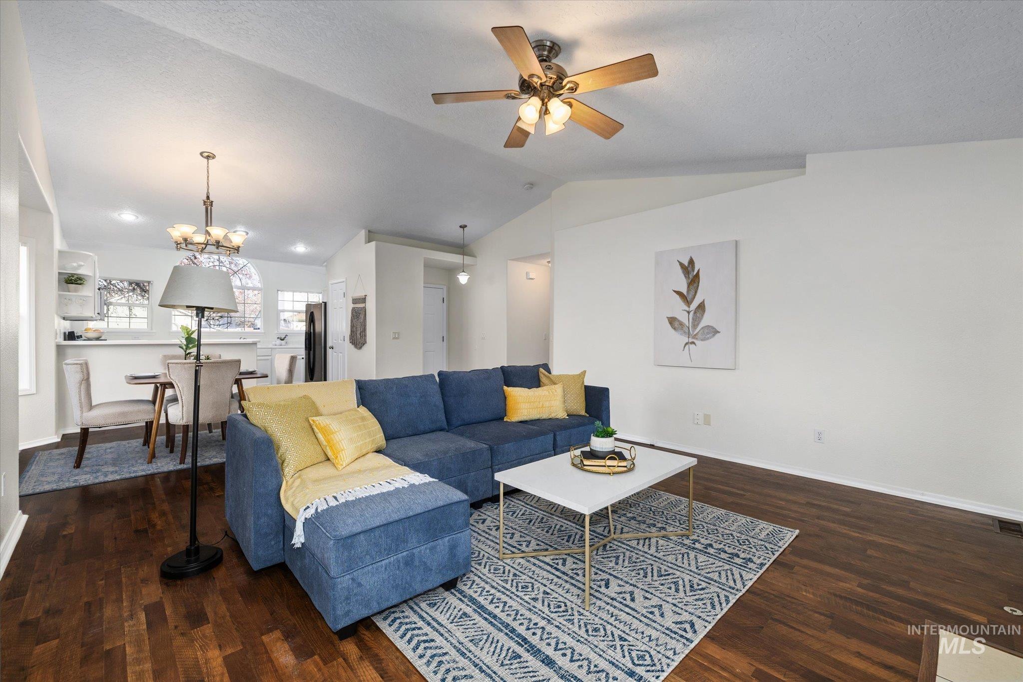 1399 West Gander Drive Meridian, ID 83642 - Photo 5 of 40 Living area with a chandelier, dark wood-style flooring, vaulted ceiling, and ceiling fan