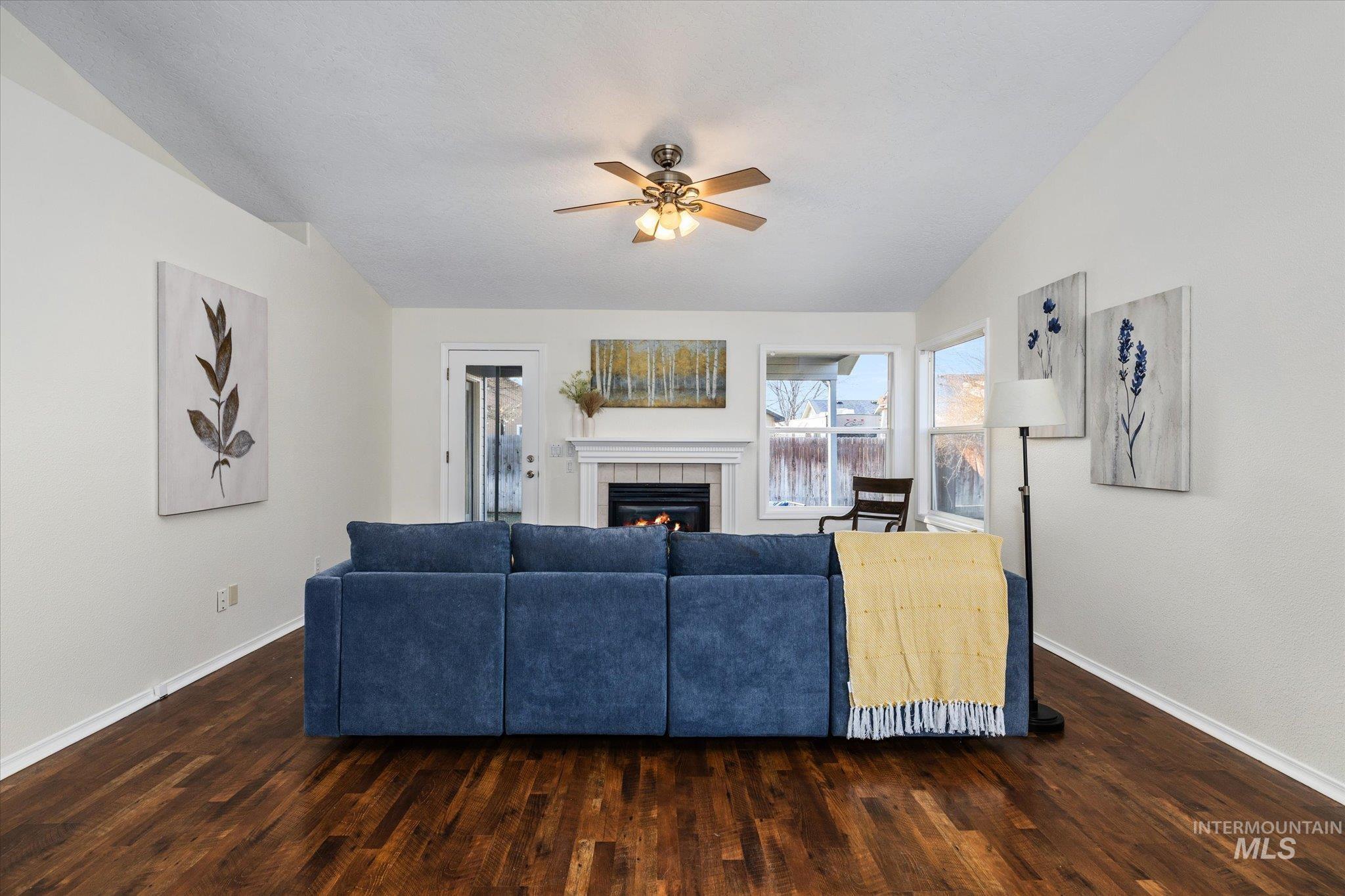 1399 West Gander Drive Meridian, ID 83642 - Photo 7 of 40 Living area featuring dark wood-style floors, a tile fireplace, and a ceiling fan