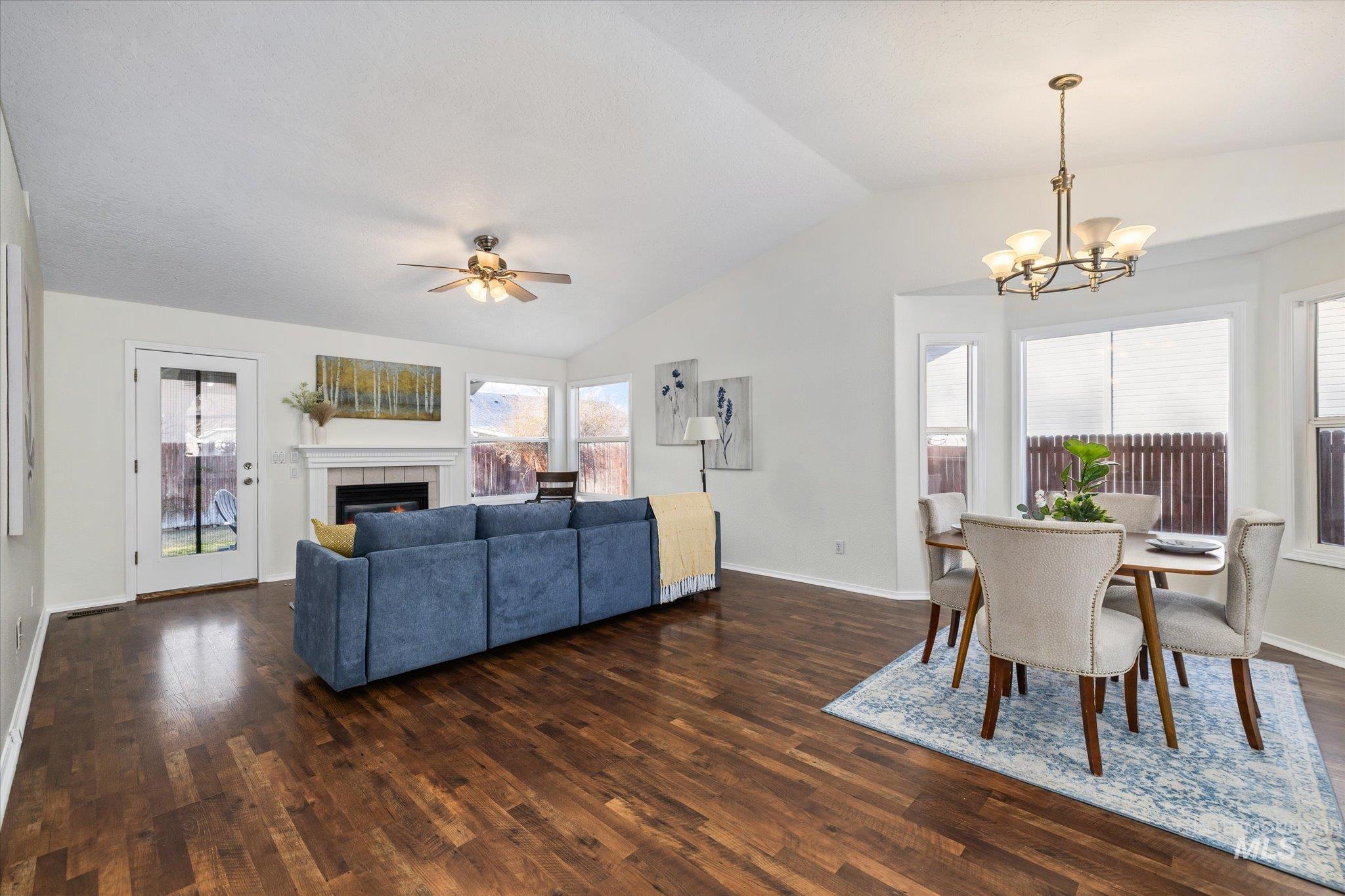 1399 West Gander Drive Meridian, ID 83642 - Photo 10 of 40 Living area featuring dark wood finished floors, lofted ceiling, ceiling fan, a chandelier, and a tile fireplace