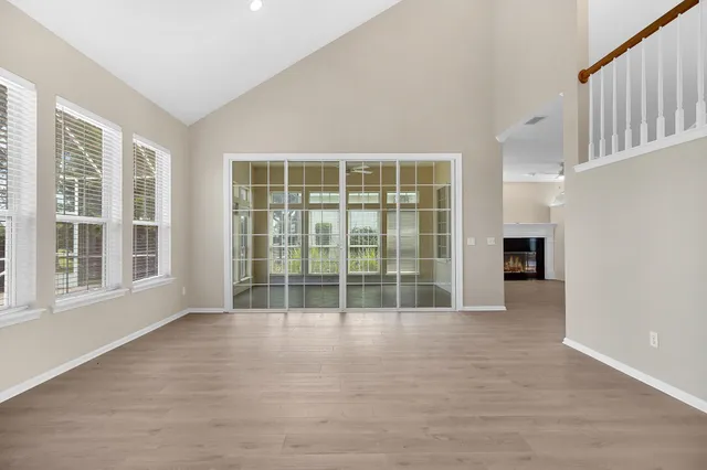 a view of an empty room with a window and wooden floor