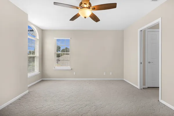 a view of an empty room with chandelier fan and window