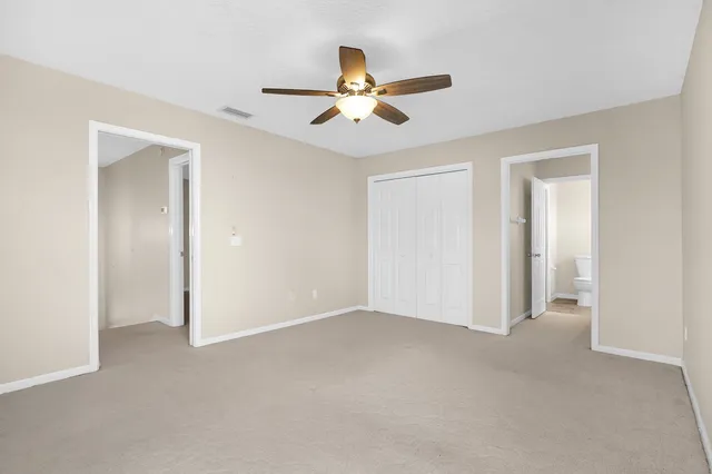 a view of an empty room and chandelier fan