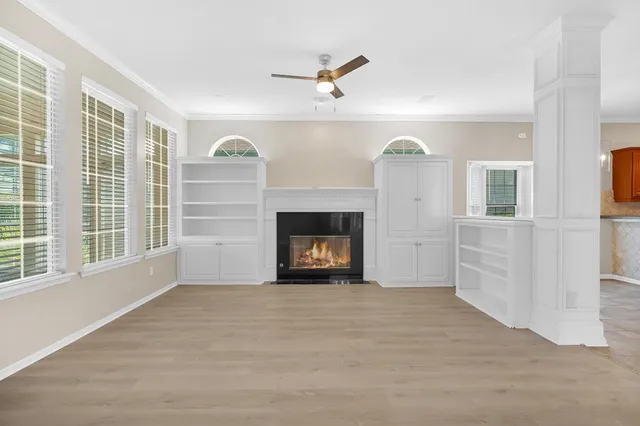 a view of a livingroom with a fireplace a ceiling fan and windows