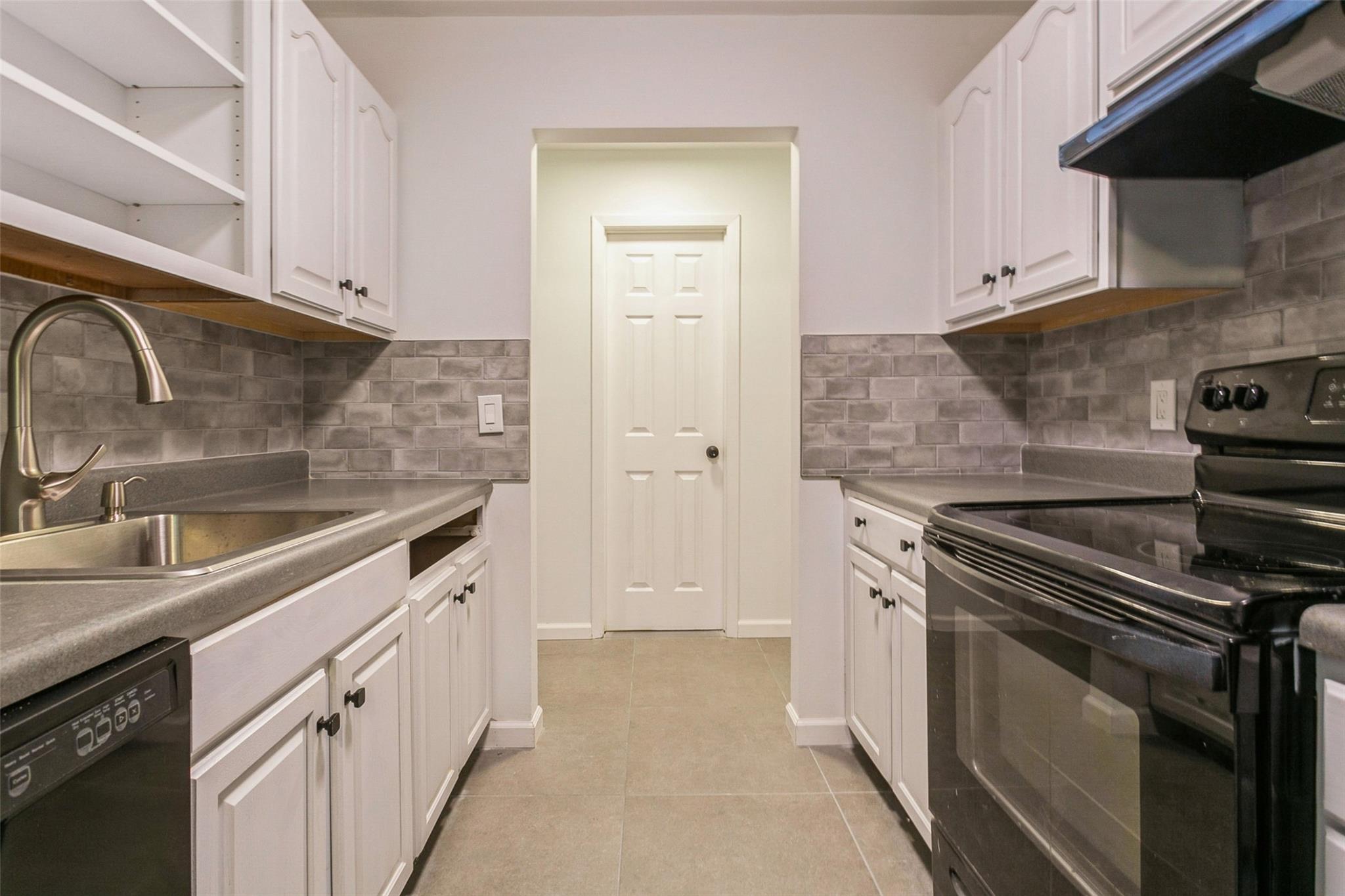 4 Rolling Way, Unit H Peekskill, NY 10566 - Photo 1 of 1 Kitchen with black appliances, light tile patterned flooring, white cabinets, and sink