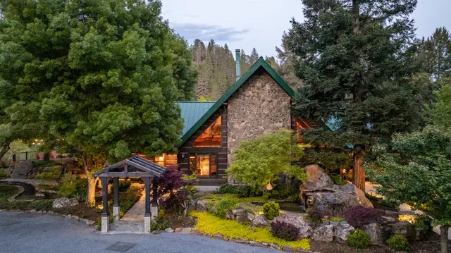 an aerial view of a house with swimming pool and trees all around
