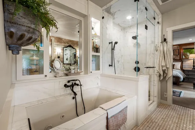 a bathroom with a tub a sink a mirror and a shower