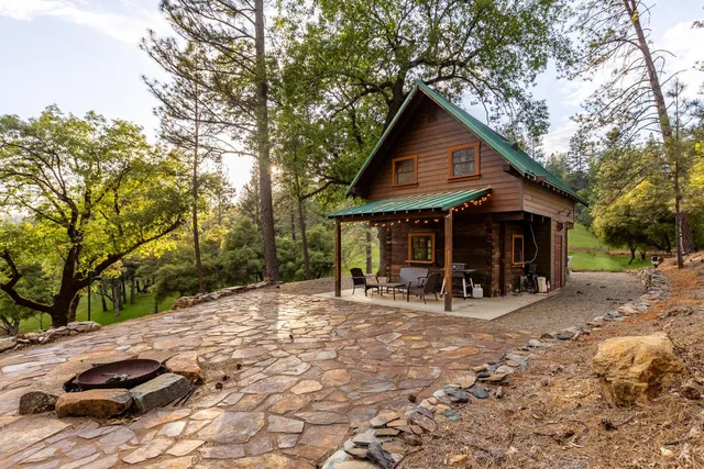 a view of a wooden house with a large trees and wooden fence