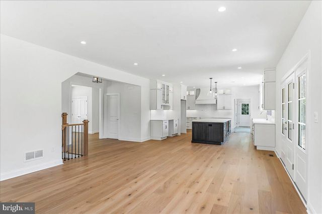 a large white kitchen with lots of counter space wooden floor and stainless steel appliances