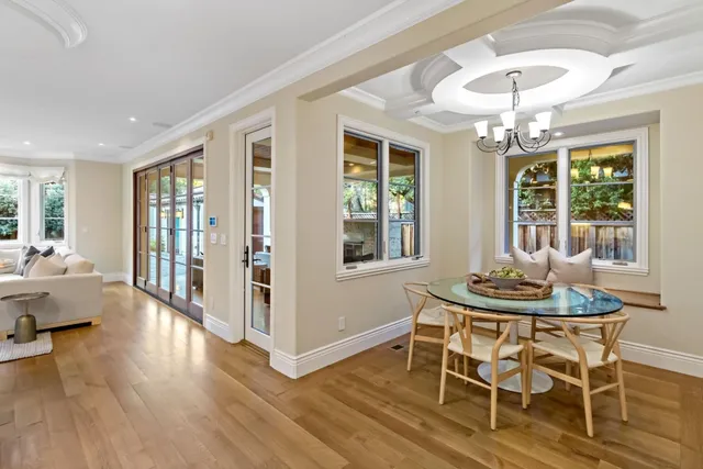 a dining room with wooden floor a chandelier a glass table and chairs