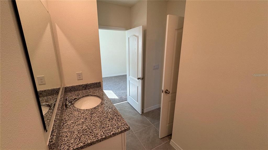 1442 Isleta Loop Kissimmee, FL 34741 - Photo 19 of 28 a bathroom with a granite countertop sink and a mirror