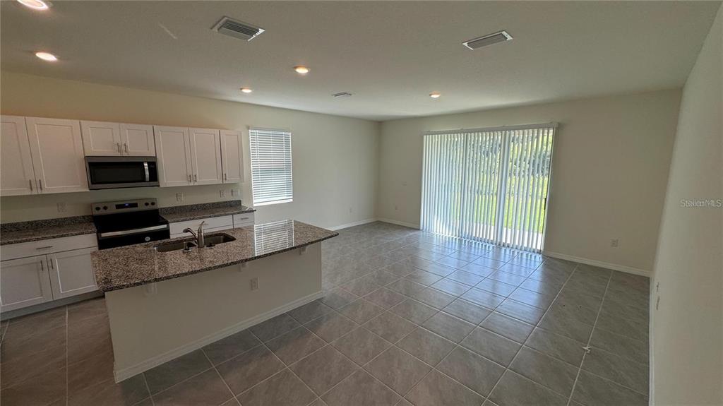 1442 Isleta Loop Kissimmee, FL 34741 - Photo 7 of 28 a large kitchen with stainless steel appliances a large counter top a stove a sink and a refrigerator