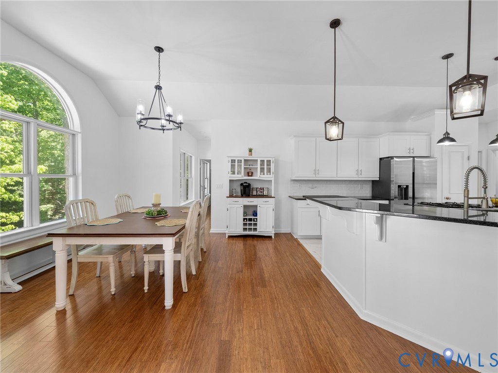 6126 Autumn Bluff Road Powhatan, VA 23139 - Photo 19 of 47 a kitchen with stainless steel appliances granite countertop a stove top oven a sink a dining table and chairs with wooden floor