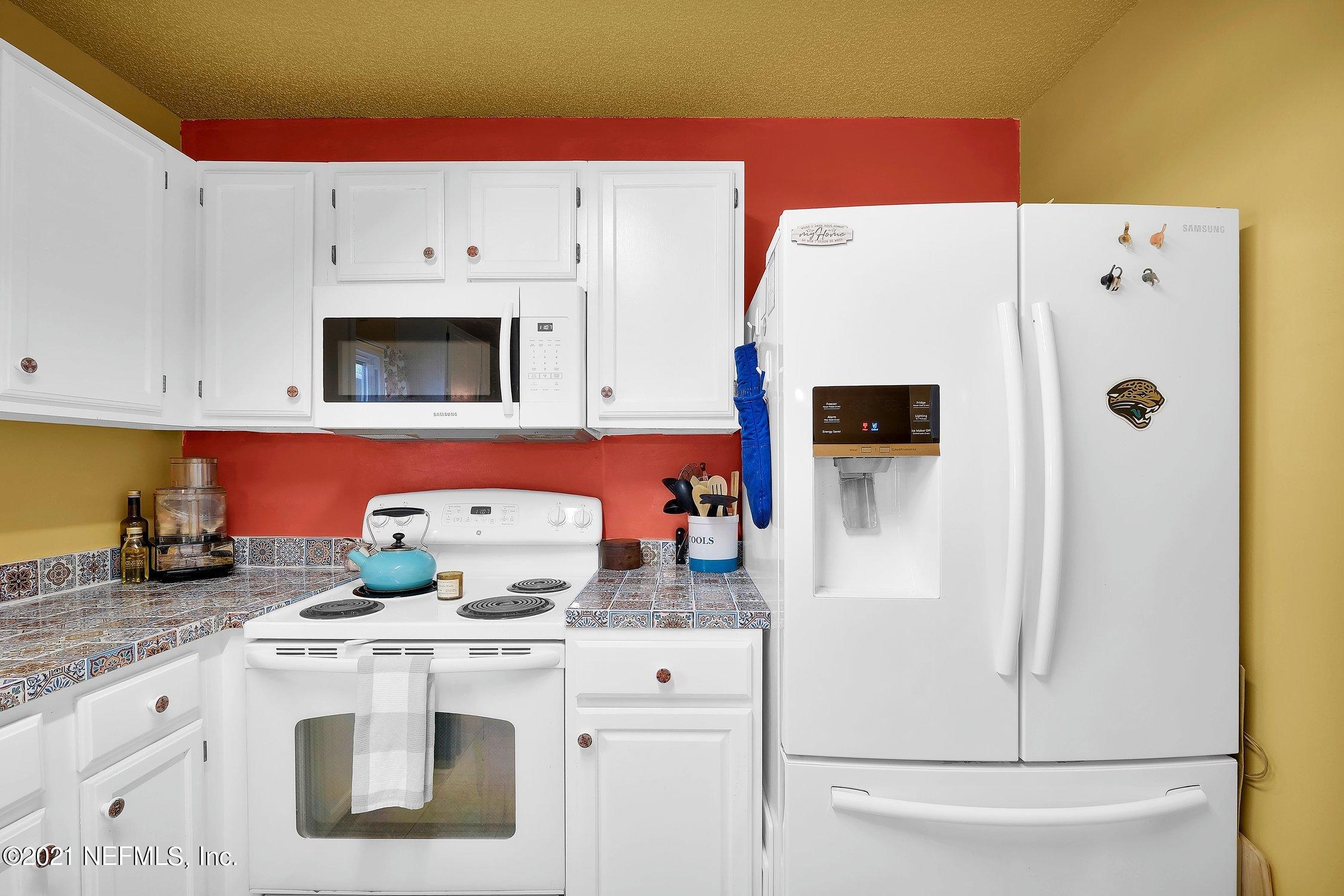 12840 Beaubien Road Jacksonville, FL 32258 - Photo 14 of 25 a white kitchen with stainless steel appliances a stove a microwave and a refrigerator