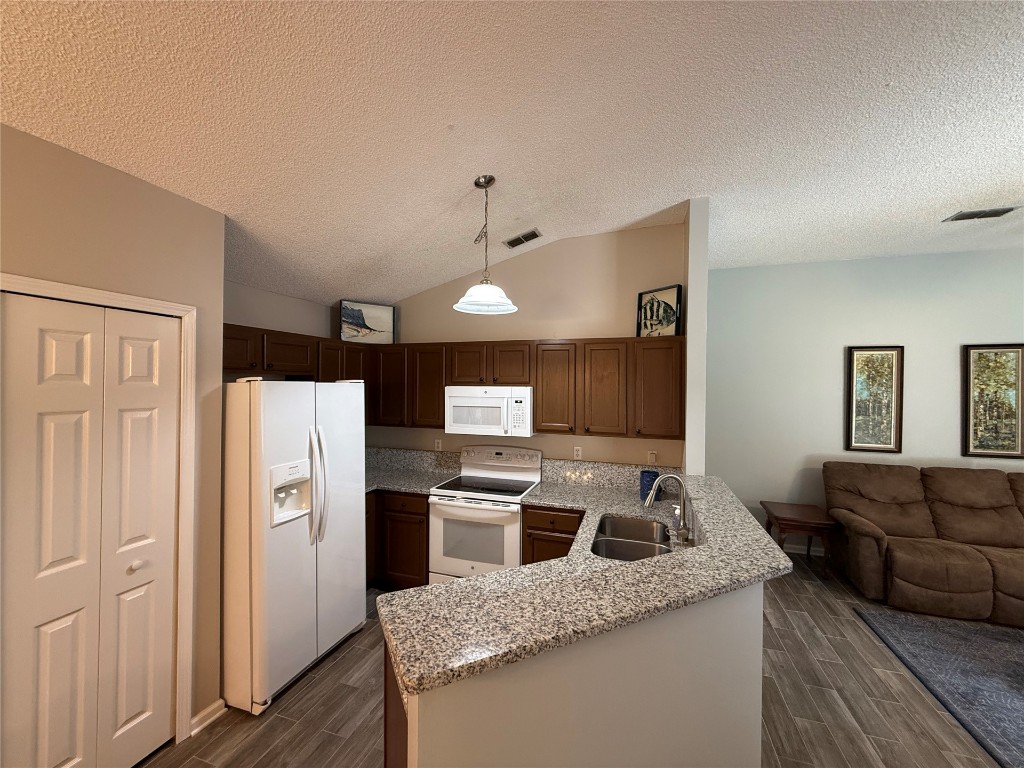 96118 Green Pine Road Yulee, FL 32097 - Photo 8 of 20 a kitchen with stainless steel appliances granite countertop a refrigerator a stove and a sink with wooden floor