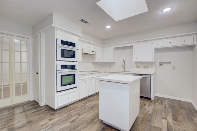 a kitchen with white cabinets appliances and sink
