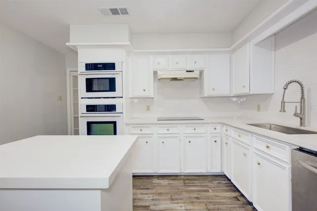 a kitchen with stainless steel appliances white cabinets and wooden floors