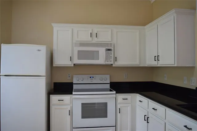 a kitchen with white cabinets and white appliances