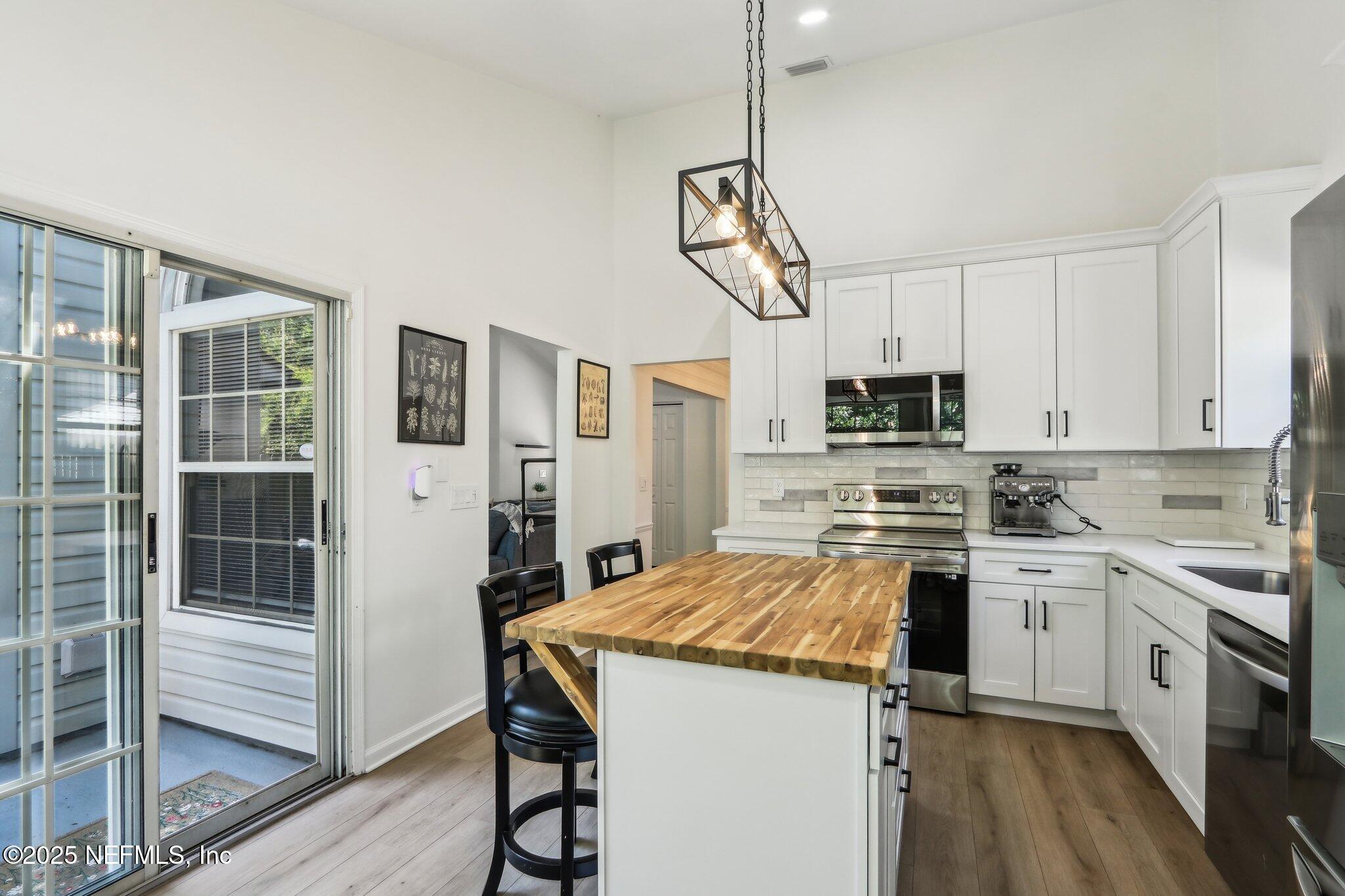 8727 Goodbys Trace Drive Jacksonville, FL 32217 - Photo 13 of 32 a kitchen with stainless steel appliances a stove a sink dishwasher a refrigerator white cabinets and wooden floor
