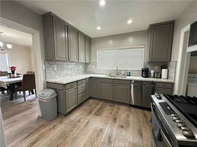 a kitchen with a sink a stove cabinets and wooden floor