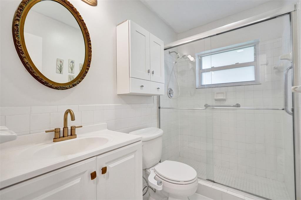 7003 Northwest 95th Terrace Tamarac, FL 33321 - Photo 29 of 44 a bathroom with a sink a mirror a toilet and a shower