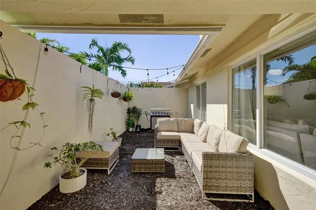 a living room with patio furniture and a potted plant